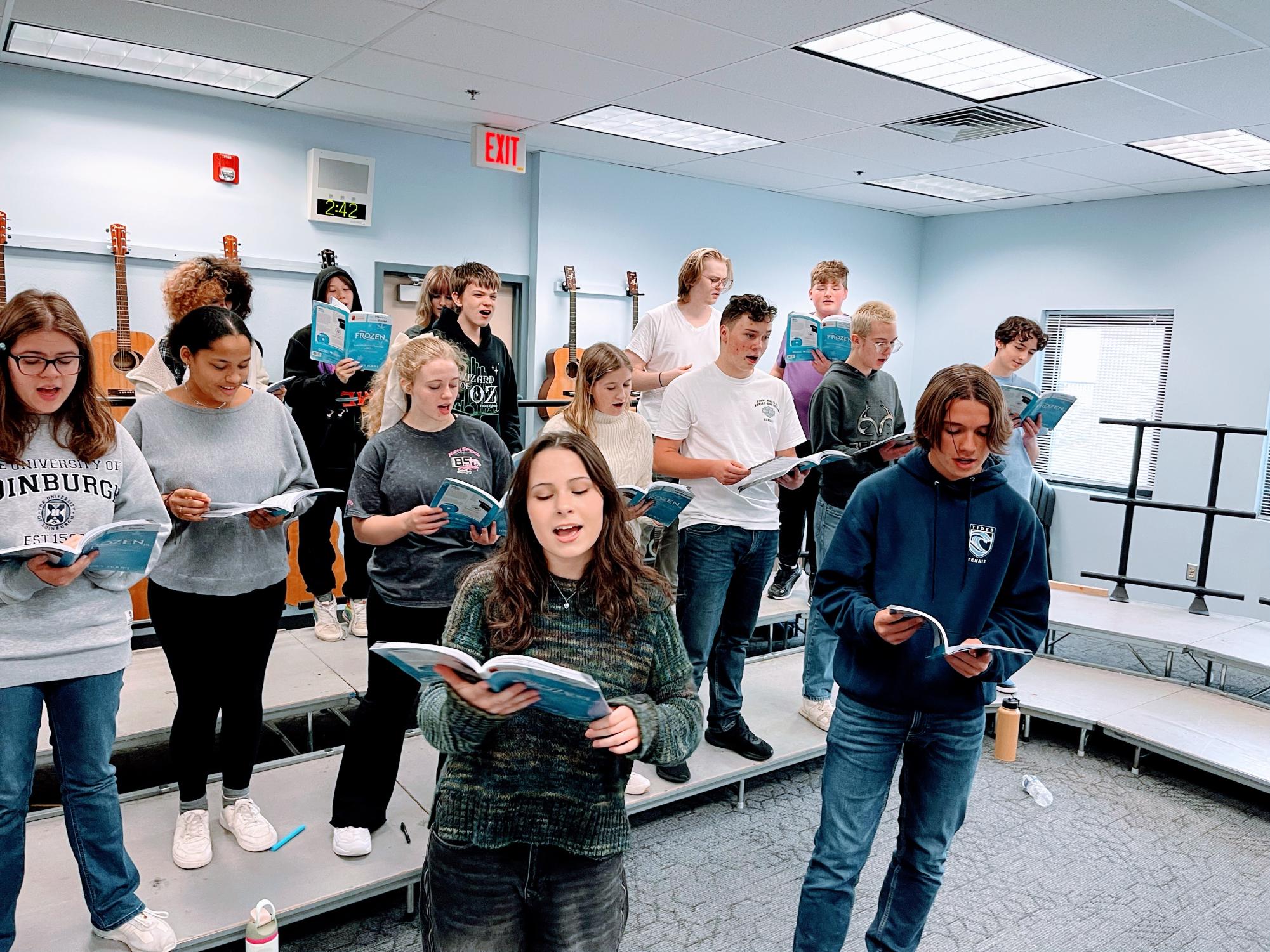 The cast practices "Love is an Open Door" in the choir room